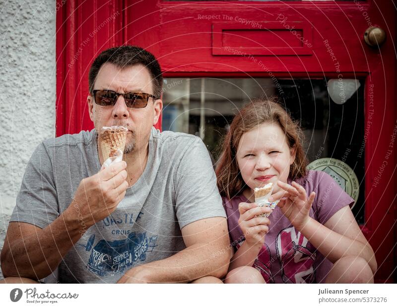Vater und Tochter essen Eiscreme Mann Mädchen Speiseeis Sitzen Sommer im Türrahmen sitzend Eis essen