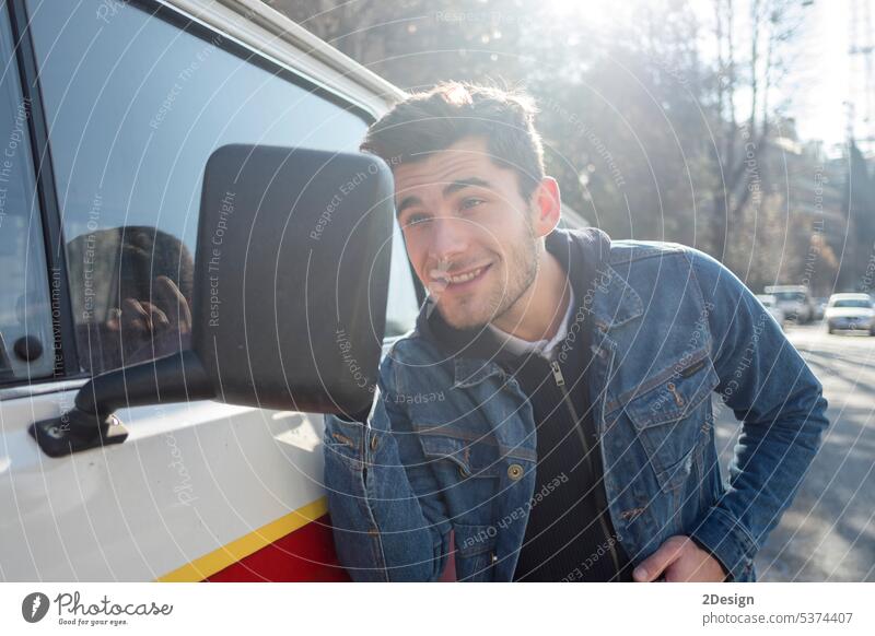 Ein junger Mann freut sich, sein hübsches Aussehen im Seitenspiegel eines Autos zu sehen. prüfen selbstbewusst Typ hispanisch horizontal Spiegel Model außerhalb