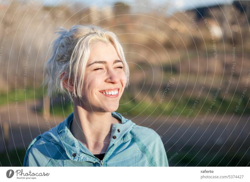 Ein Porträt einer lächelnden blonden Frau mit geschlossenen Augen nach dem Joggen Pferdeschwanz Person schön jung Läufer zahnfarben Sport Lächeln Kaukasier