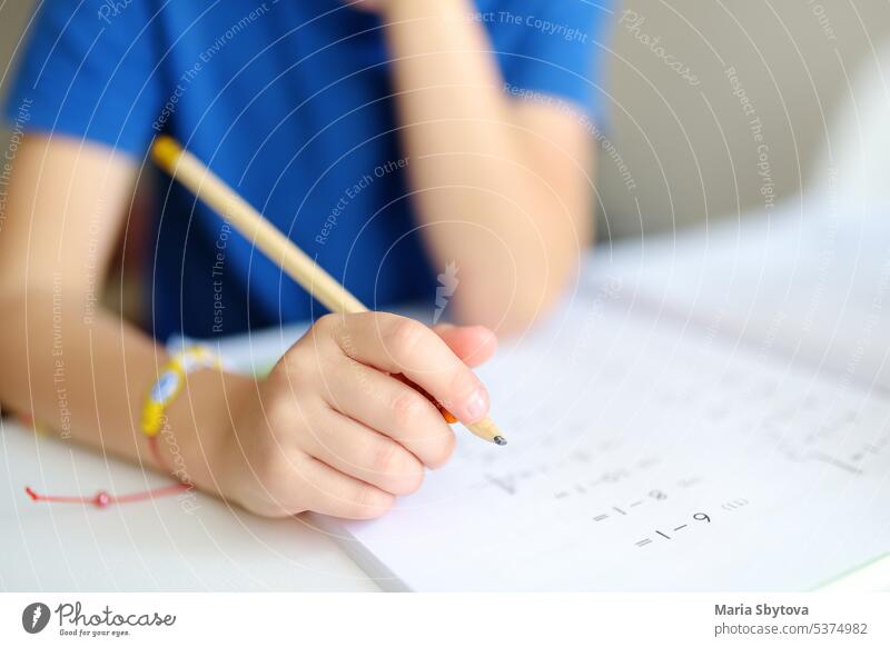 Grundschüler Junge macht Hausaufgaben zu Hause. Kind lernt zu zählen, löst arithmetische Beispiele, macht Übungen im Arbeitsbuch. Mathe-Tutorial. Preparing Vorschüler Baby für die Schule. Bildung
