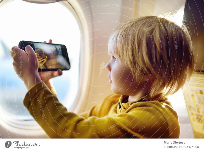 Ein kleiner Junge nimmt mit seinem Smartphone einen Blick auf den Flugplatz vom Beleuchtungsflugzeug aus auf. nehmen Schuss Ebene Illuminator Fluggerät Blogger
