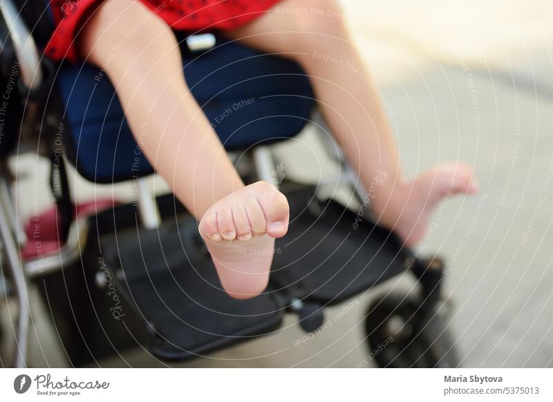Behindertes Mädchen sitzt im Rollstuhl. Nahaufnahme der spastischen Muskeln ihrer Beine. Kind zerebrale Lähmung. Behinderung. Inklusion. deaktiviert