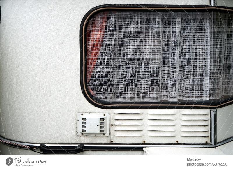 Weißer Wohnwagen für Vanlife und Camping mit Gardine am Fenster im Stil der frühen Fünfziger Jahre im Lenkwerk in Bielefeld im Teutoburger Wald in Ostwestfalen-Lippe