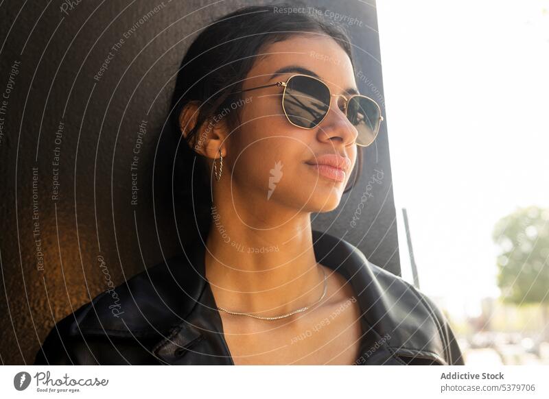 Positive Frau mit Sonnenbrille auf der Straße selbstbewusst cool Stil positiv trendy urban Lederjacke Persönlichkeit ernst Jacke Individualität stehen Vorschein