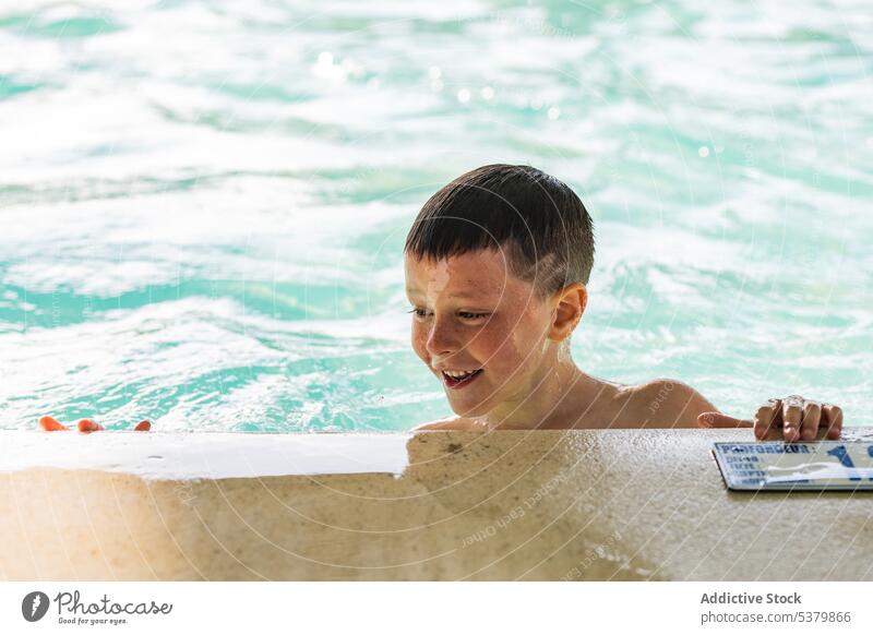 Fröhlicher Kinderschwimmer mit Buch am Meer Junge Wasser Lächeln ohne Hemd Sommer MEER Saum Natur genießen Freude Beton Kindheit positiv tagsüber heiter Ufer