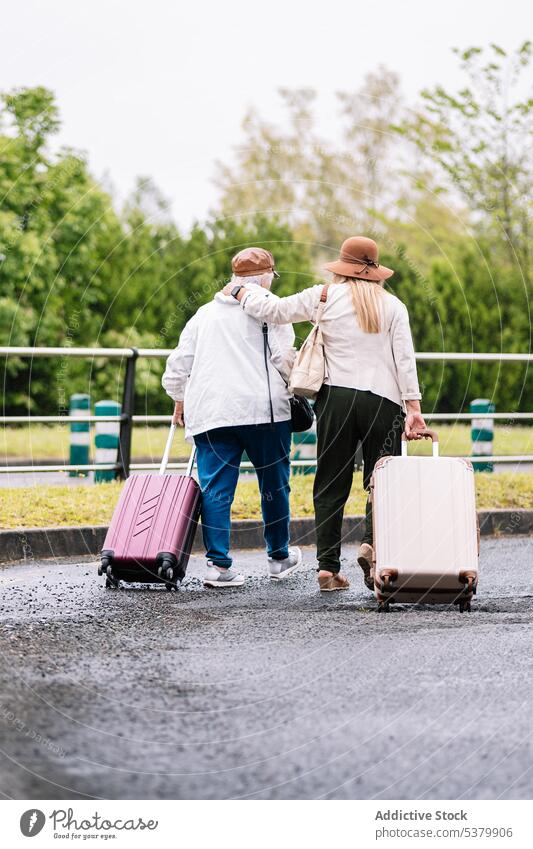 Anonyme ältere Frauen mit Koffern gehen umarmend die Straße entlang Reisender Umarmen Umarmung Spaziergang Ausflug Gepäck Urlaub Zusammensein reisen Senior