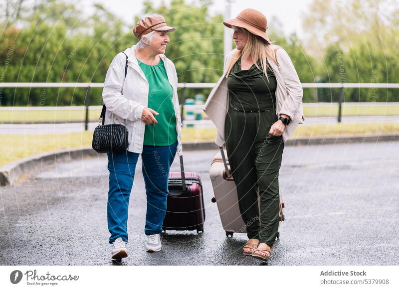 Glückliche ältere Frauen mit Koffern auf der Straße Reisender Spaziergang Ausflug Gepäck Urlaub Zusammensein reden Lächeln reisen Senior Sommer Freund Feiertag