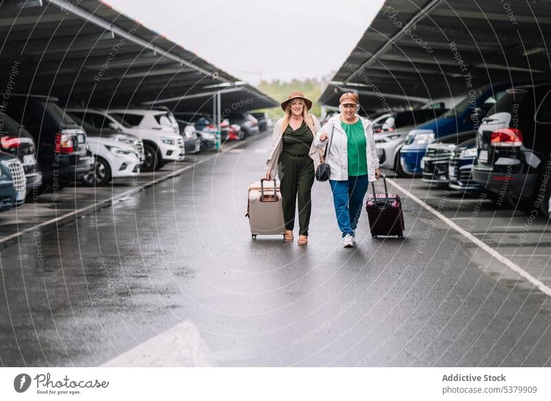 Ältere Frauen mit Koffern gehen auf einem Parkplatz Urlaub Gepäck Reisender parken Zusammensein Spaziergang Glück Ausflug reisen Asphalt Feiertag Tourismus