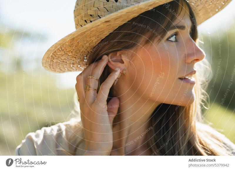 Junge Frau mit Strohhut in der Landschaft stehend Lächeln Tastkopf Porträt Glück Urlaub Optimist froh Sommer jung heiter Sonnenlicht gestikulieren positiv