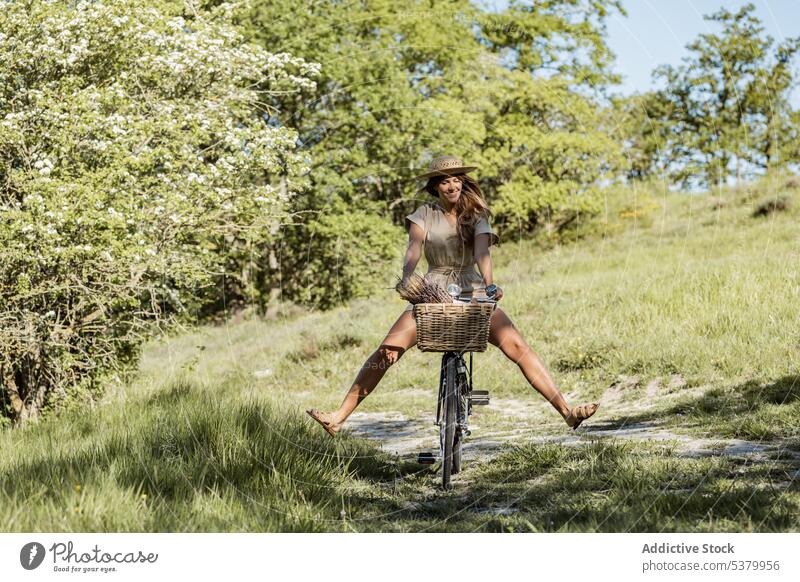 Fröhliche Frau beim Fahrradfahren auf dem Lande Landschaft Mitfahrgelegenheit Beine hoch Natur Sommerzeit Spaß haben Freude heiter sorgenfrei Glück jung