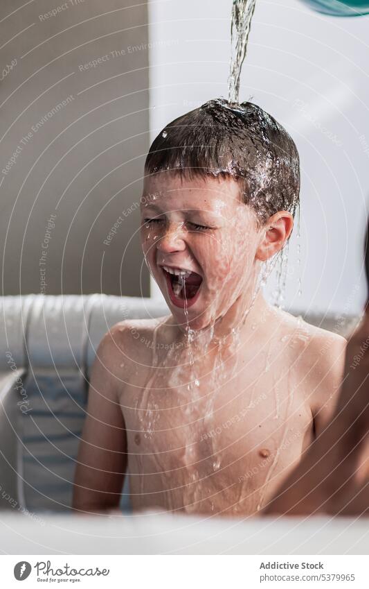 Aufgeregtes Kind, das mit geschlossenen Augen im Kinderbecken schreit Junge schreien Wasser Mund geöffnet Spaß haben Augen geschlossen Glück spielen nasses Haar