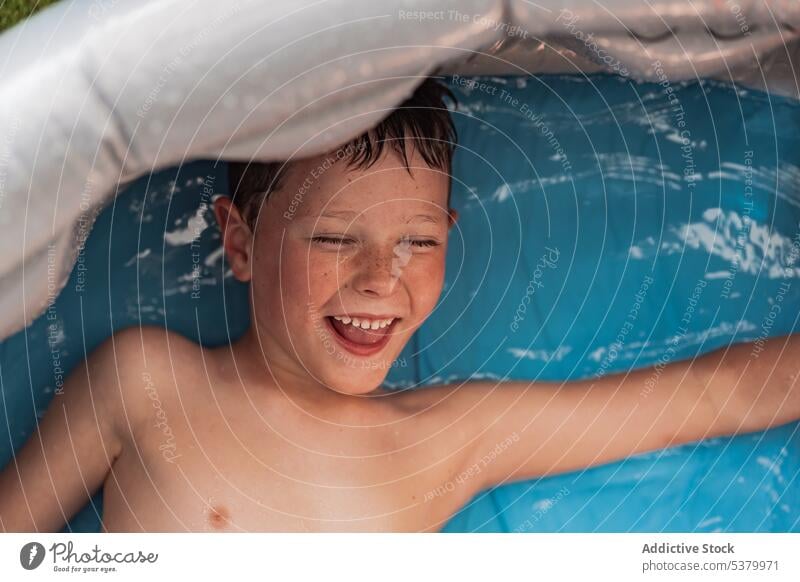 Glückliches Kind ohne Hemd im Pool mit blauem Wasser liegend sich[Akk] entspannen Lächeln Badewanne heiter Lügen positiv genießen Hygiene Junge Wochenende