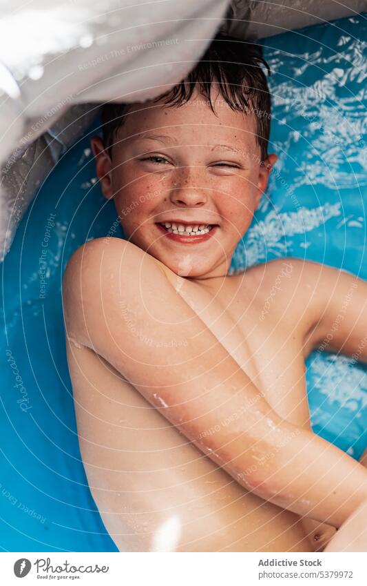 Fröhlicher Junge ohne Hemd im Pool mit blauem Wasser liegend Kind sich[Akk] entspannen Lächeln Badewanne heiter Lügen positiv genießen Hygiene Wochenende Freude