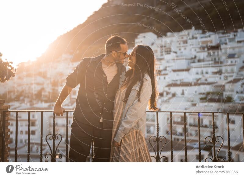 Verliebtes Paar auf dem Balkon stehend Lächeln Umarmung Sonnenuntergang Berge u. Gebirge Großstadt Abend Partnerschaft Sommer jung Glück Liebe Umarmen
