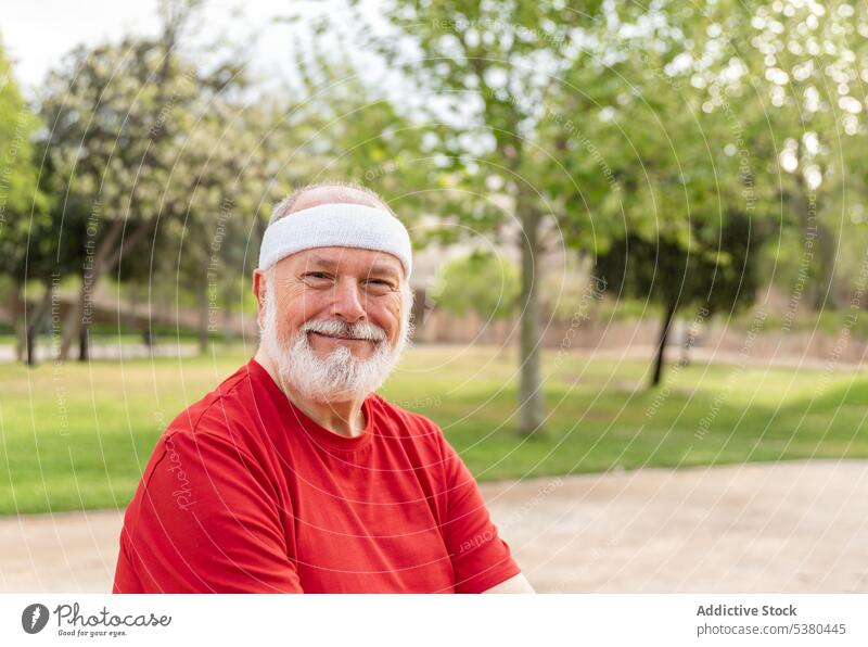 Glücklicher älterer Mann lächelt in die Kamera im Park Athlet Fitness Sport positiv Lächeln Wohlbefinden Porträt Gesunder Lebensstil selbstbewusst männlich