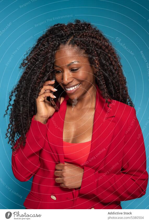 Lächelnde Frau in roter modischer Kleidung, die mit ihrem Smartphone spricht reden Telefonanruf sprechen Mode Stil schwarz jung Outfit heiter Gespräch Glück