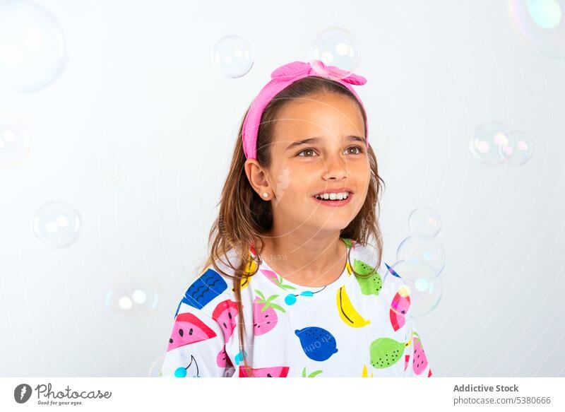Glückliches Mädchen in buntem Outfit mit Seifenblasen farbenfroh Kind Lächeln positiv Kindheit wenig Stirnband Optimist genießen Spaß haben Vorschule Porträt