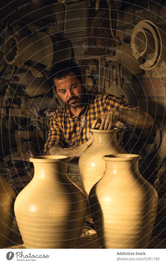 Fokussierter Mann, der eine Vase auf einer Töpferscheibe in einer Werkstatt formt Töpferwaren Arbeit Handwerk Kunsthandwerker Ton Tradition Kunstgewerbler