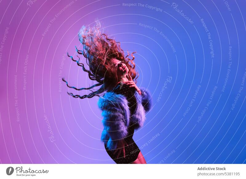 Stilvolle Frau in Pelzjacke tanzen gegen bunten Hintergrund Model 80s fliegendes Haar Tanzen retro sich[Akk] bewegen Charme Party jung helles Haar