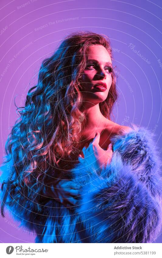 Stilvolle junge Frau mit blauer Pelzjacke Model 80s Fell festlich retro Charme Make-up neonfarbig helles Haar Frisur Individualität Jacke Vorschein pulsierend
