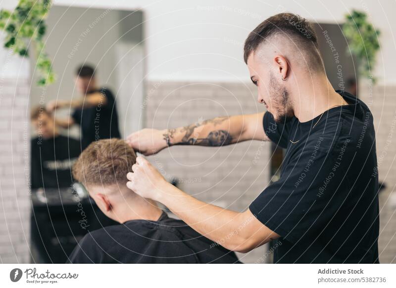 Junger Friseur schneidet Haare mit Maschine Hintergrund Barbershop Vollbart bärtig Bartiger Mann Schönheit Klinge Pflege Klient Ausschnitt Frisur Kutter