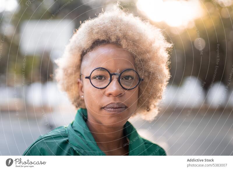 Seriöse schwarze Frau mit lockigem Haar auf der Straße Porträt krause Haare Stil Großstadt Vorschein Afroamerikaner ethnisch Afro-Look froh Freude feminin