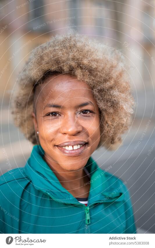 Lächelnde schwarze Frau mit lockigem Haar auf der Straße Porträt positiv heiter Glück krause Haare Inhalt Stil Großstadt Vorschein Afroamerikaner ethnisch