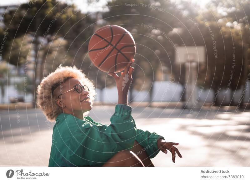 Glückliche schwarze Frau hält Basketball hoch Spieler Ball Gericht Sportpark Sportlerin Park Training Fokus Sportbekleidung sich[Akk] entspannen Stil