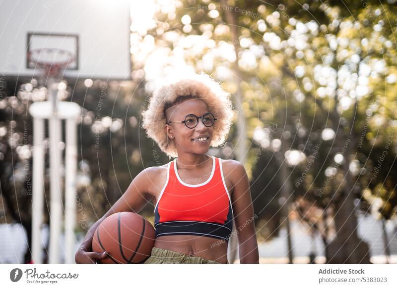 Fröhliche schwarze Sportlerin mit Basketball auf der Straße Spieler Frau Ball Athlet Park jung Afroamerikaner spielen Gericht Inhalt Lifestyle Lächeln Training