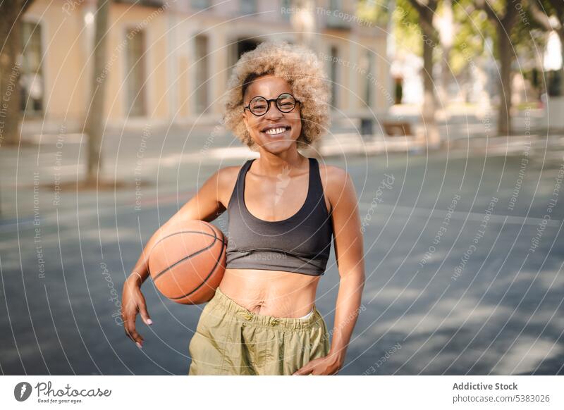 Fröhliche schwarze Sportlerin mit Basketball auf der Straße Spieler Frau Ball Athlet Park jung Afroamerikaner spielen Gericht Inhalt Lifestyle Lächeln Training
