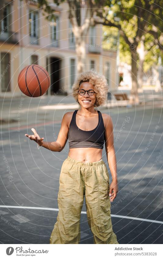 Fröhliche schwarze Sportlerin mit Basketball auf der Straße heiter Ball werfen Spieler spielen Athlet Afroamerikaner jung Frau Gericht Lächeln Glück positiv