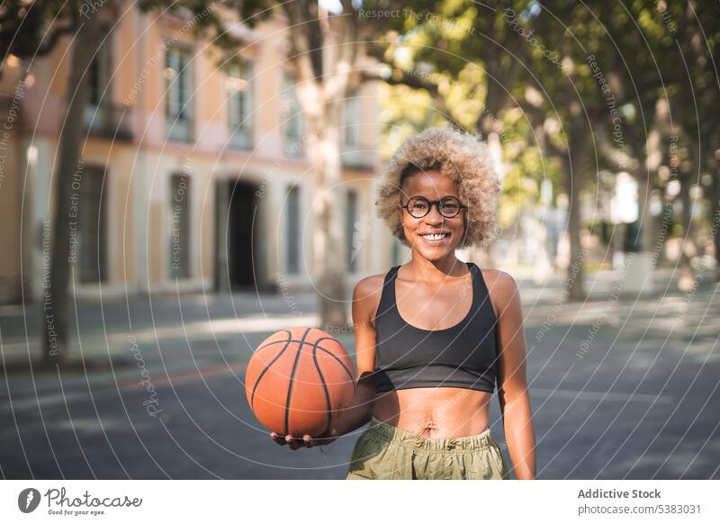 Fröhliche schwarze Sportlerin mit Basketball auf der Straße heiter Ball werfen Spieler spielen Athlet Afroamerikaner jung Frau Gericht Lächeln Glück positiv