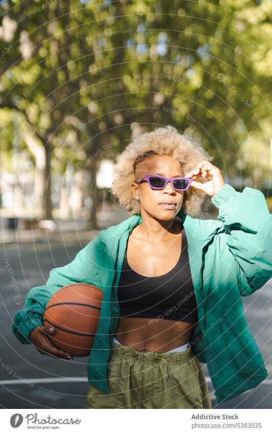 Seriöse Frau mit modischer Sonnenbrille und Basketball auf der Straße Porträt Stil trendy selbstbewusst Großstadt Sommer modern jung urban Outfit Vorschein