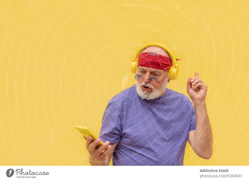 Älterer Mann mit Kopfhörern und Smartphone Musik zuhören Tanzen benutzend Gerät Apparatur Glück positiv modern älter männlich lässig Stil Klang Telefon Gesang