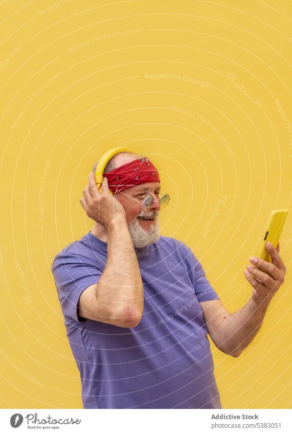 Seitenansicht älterer Mann mit Kopfhörern und Smartphone Musik zuhören benutzend Gerät Apparatur Glück positiv modern Lächeln männlich lässig Stil Klang Telefon