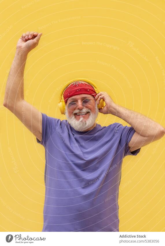 Aufgeregter Mann mit geschlossenen Augen, der über Kopfhörer Musik genießt aufgeregt Lächeln Tanzen zuhören Glück Porträt genießen Senior männlich Gesang lässig