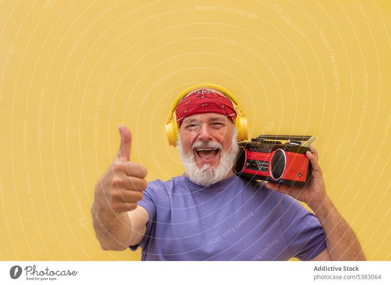 Lächelnder Mann mit Kassettenspieler, der den Daumen nach oben zeigt OK Zeichen Daumen hoch mögen gestikulieren altehrwürdig retro Musik Glück Kopfhörer
