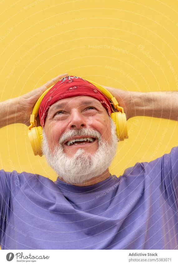 Glücklicher Mann mit Kopfhörern beim Musikhören heiter zuhören Hipster Porträt Apparatur Schal positiv Melodie Senior alt Vollbart männlich Klang meloman älter