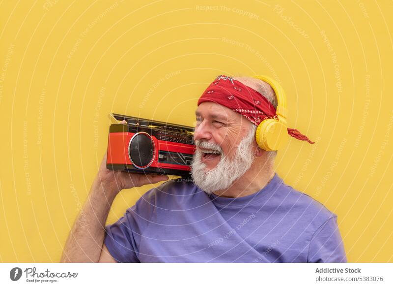 Glücklicher älterer Mann mit Kopfhörern beim Musikhören Porträt zuhören Kassette Gerät Apparatur Klang gealtert Stimme Vollbart Gesang Audio Atelier männlich