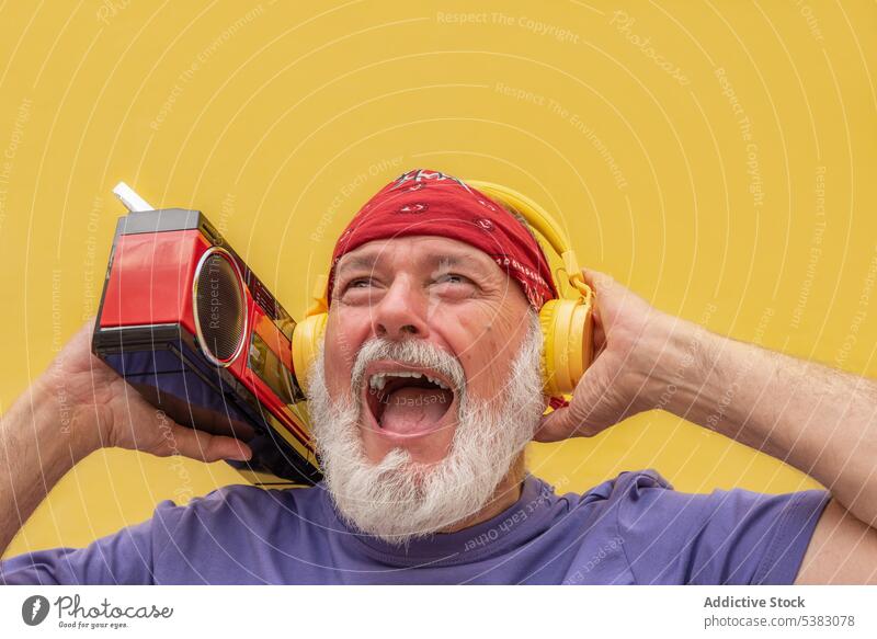 Aufgeregter älterer Mann mit Kopfhörern, der Musik hört Porträt zuhören Kassette gestikulieren Gerät schreien Schrei Apparatur Klang gealtert Stimme Vollbart