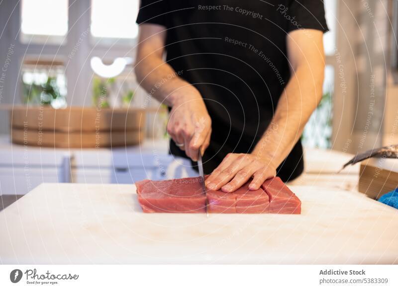 Crop männlicher Koch schneidet Stück Thunfisch Mann Küchenchef geschnitten roh Fisch kulinarisch vorbereiten Lebensmittel Restaurant Arbeit Spielfigur Tisch