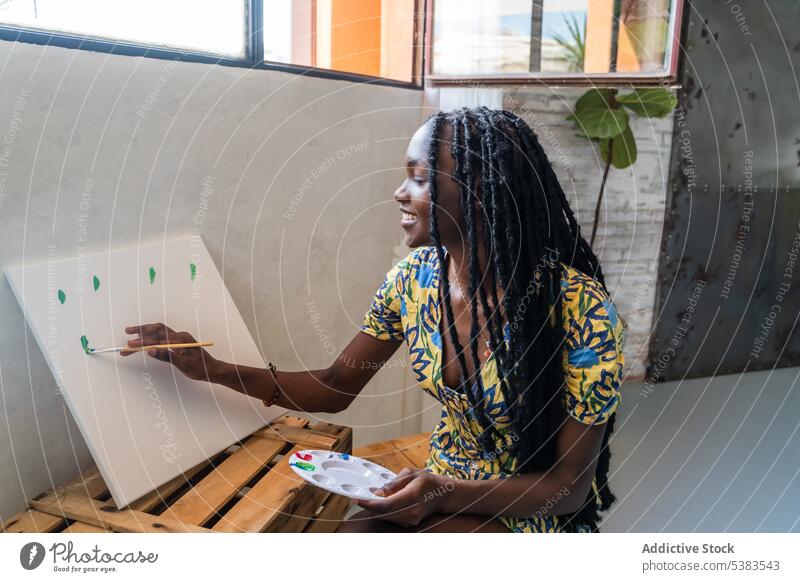 Glückliche schwarze Frau malt im Atelier auf Leinwand Künstler Farbe Pinselblume kreativ Zeichnung Kunst Fähigkeit Hobby Freizeit Werkstatt Talent Inspiration