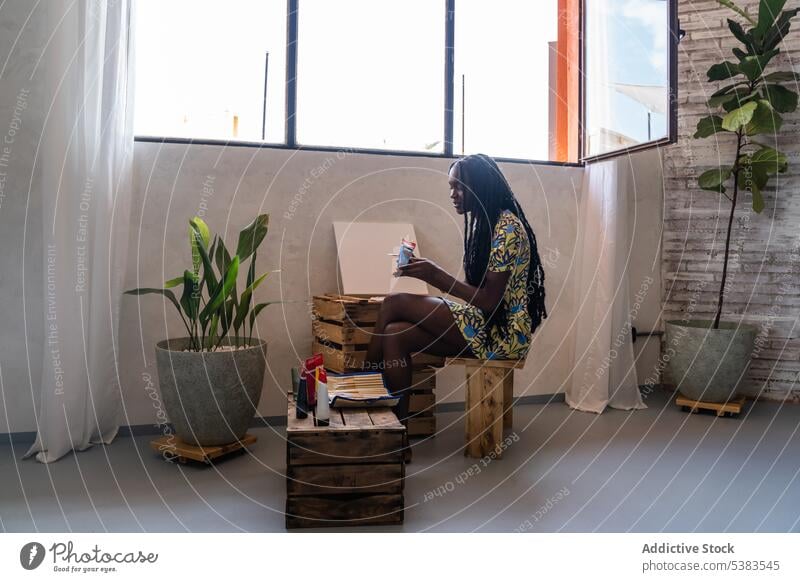 Positive schwarze Frau, die in einer Werkstatt Farbe auf eine Palette aufträgt Künstler Leinwand setzen Kunst Lächeln Fähigkeit Atelier Talent Hobby jung Acryl