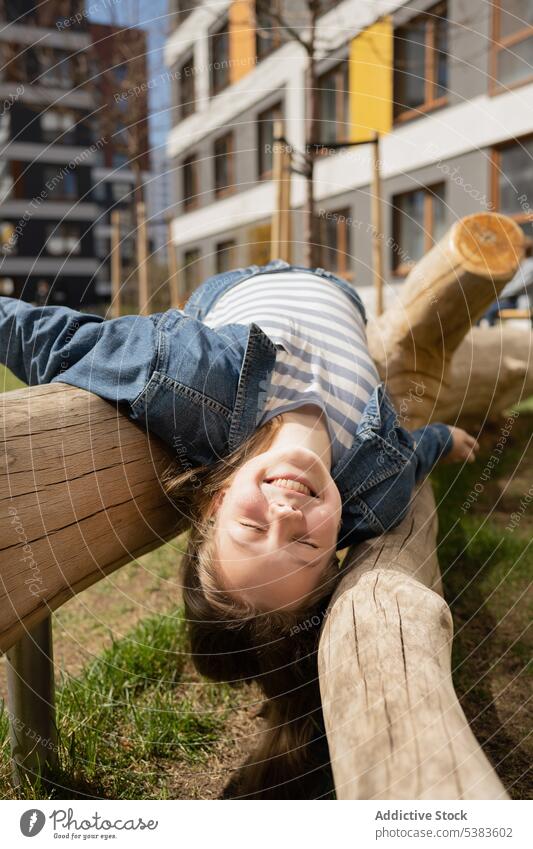 Fröhliches Teenager-Mädchen liegt auf einem Baumstamm im Park Lügen Totholz genießen spielerisch Sommer Glück sorgenfrei Lächeln Kälte jung Wochenende Freude
