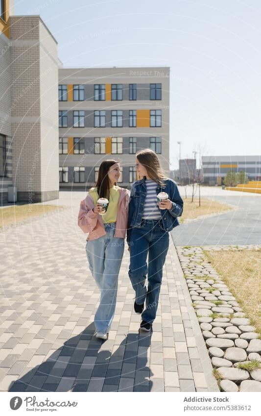 Teenager-Freunde schlendern zusammen auf dem Bürgersteig in der Stadt Mädchen Händchenhalten Spaziergang Straßenbelag Zusammensein Freizeit Bonden sorgenfrei