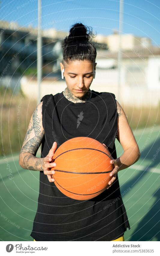 Coole ernste Frau hält Basketball auf dem Spielplatz Sportlerin Spieler Ball spielen Streetball Tattoo Training maskulin brutal androgyn Sportbekleidung Gericht