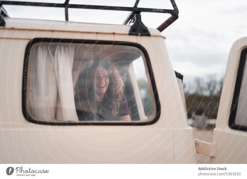 Lächelnde junge Frau, die in einem geparkten Lieferwagen mit geöffneter Hintertür sitzt Fenster positiv Tür froh Sommer Glück heiter Kleintransporter Fahrzeug