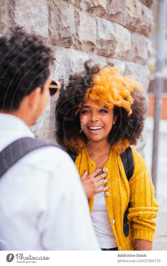 Fröhliches multiethnisches Paar steht zusammen auf der Straße Partnerschaft Lächeln heiter Großstadt Wand Zeit verbringen anonym Rucksack positiv Glück jung