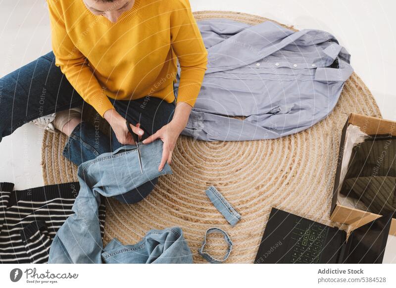 Frau schneidet Kleidung Konzentration Fokus Rudel Stoff Paket vorbereiten zu Hause Bekleidung heimwärts Wohnzimmer benutzend Arbeit geschnitten reif lässig