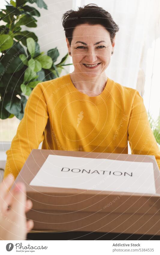 Glückliche Frau mit Spendendose Lächeln Geldgeschenk schenken Almosen Kollo geben Freiwilliger Kasten Appartement positiv Geschenk heiter Raum Arbeit Freude